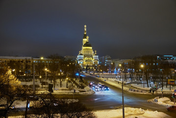 Obraz premium Night city in winter. Machines and street lights. The big cathedral is highlighted