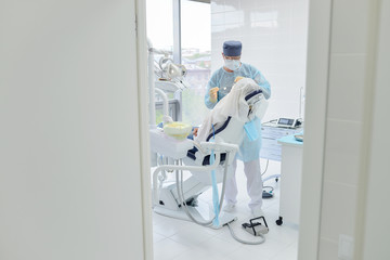 Dental surgery operation in modern dentist clinic, looking thru opened door.