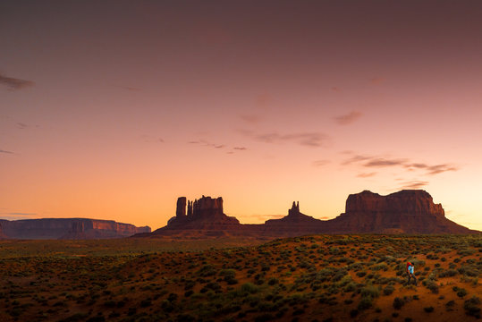 Backpacker Hiking at Monument Valley Utah USA Landscape At Dusk Under Colorful Red Tobacco Sky
