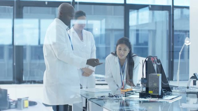 Electronics engineers working in lab, building components with 3D printer