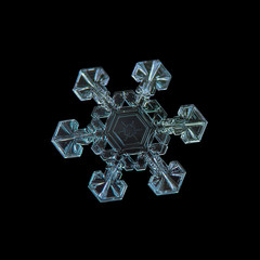 Snowflake isolated on black background. Macro photo of real snow crystal: large star plate with six short, simple arms, fine hexagonal symmetry and unusual pattern inside central hexagon.