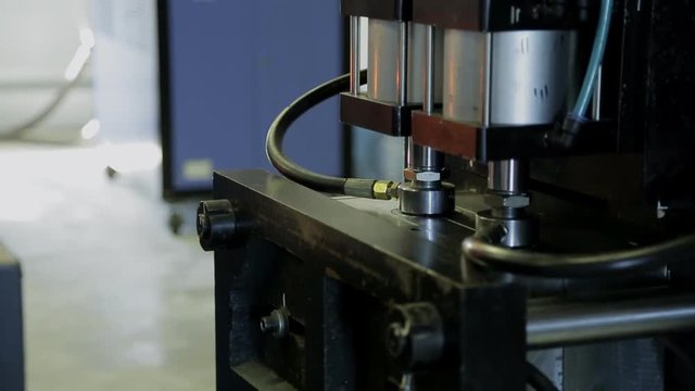Employee of plant puts preforms in a machine for making bottles. Hands of worker performs loading from two blanks for blowing out plastic container.