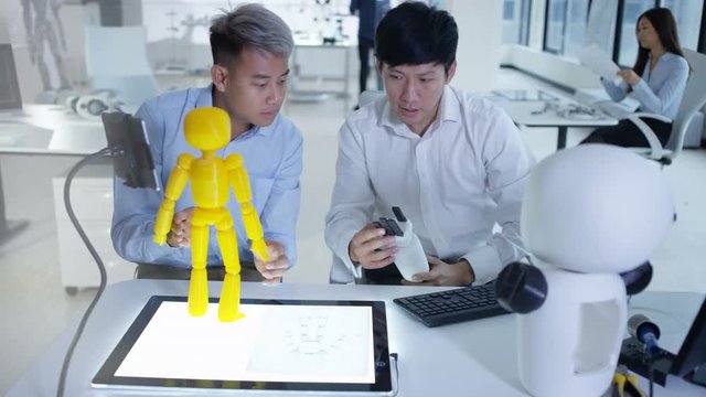  Asian electronics engineers working in the lab with robot prototype