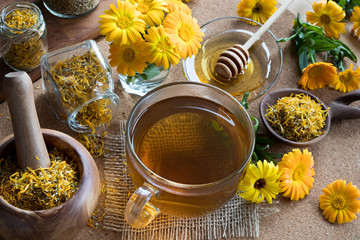A cup of calendula tea with calendula in the background