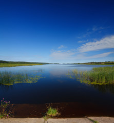 Panoramic view of the smooth surface of the lake with vegetation