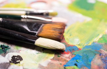 Obraz premium Artist paint brushes and oil paint on wooden artistic palette background. Brush paint artistic. Tools for creative work. Back to school. Paintings Art Concept. Selective focus. Copy space.