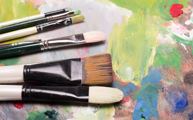 Obraz premium Artist paint brushes and oil paint on wooden artistic palette background. Brush paint artistic. Tools for creative work. Back to school. Paintings Art Concept. Selective focus. Copy space. Top view.