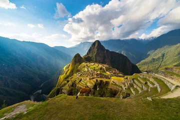 Photo sur Plexiglas Machu Picchu Machu Picchu illuminé par la chaude lumière du coucher du soleil. Vue grand angle depuis les terrasses au-dessus avec ciel panoramique et éclat de soleil. Destination de voyage onirique, merveille du monde. Région de Cuzco, Pérou.