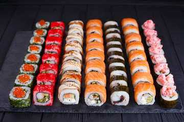 Delicious fresh multicolored sushi set on black slate. Traditional japanese food, restaurant serving