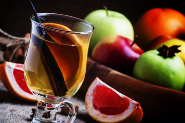 Winter hot mulled white wine with vanilla, grapefruit and cinnamon, vintage wooden background, selective focus