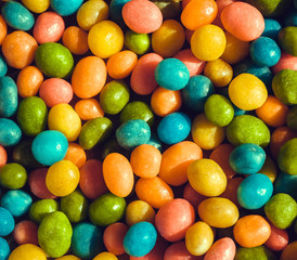 Fototapeta na wymiar Heap of candy confections small many green, yellow, blue colors. Bright texture and round forms of sweets in sugar