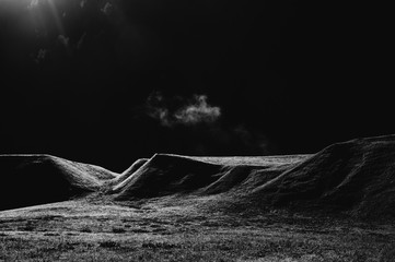 Lonely cloud above the field in the morning. Black and white image
