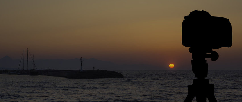 Camera on tripod with sea and sunset in background / Gouves, Crete, Greece 