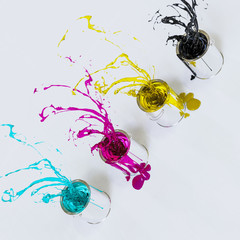 Fontänen aus den Druckfarben CMYK spritzen aus vier Eimern in den Raum