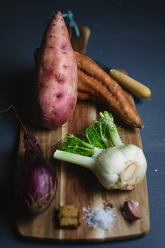Ingredients for making roasted sweet potato and fennel soup on wooden board.