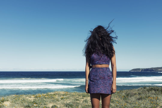 Woman with long hair covering face standing on beach on windy day