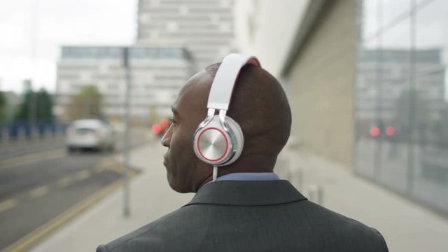  Laid back businessman listening to music & dancing as he walks to work