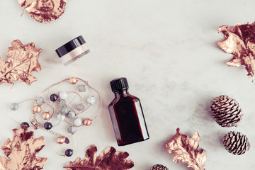 Fall beauty products and accessories with rose gold leaves on white marble table from above. Copy space
