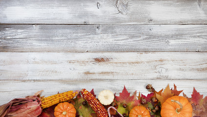 Bottom border of Autumn foliage with other fall decorations on white rustic wooden boards for thanksgiving holiday season  - 175539779