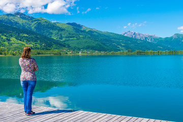 Naklejka premium A young pretty girl dreams near a mountain lake.