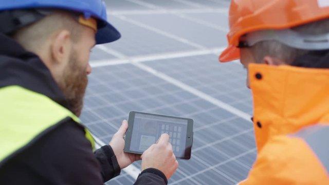  Technicians with tablet checking the panels at solar energy installation