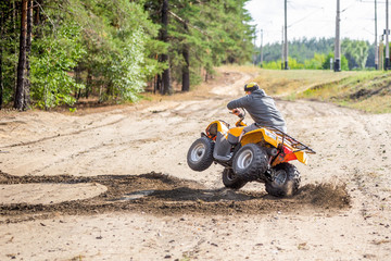 An ATV quadbike driver drifts and stunts on a sand rough terrain near forest, turns on a two wheels in a moment before acciden © Kirill Gorlov
