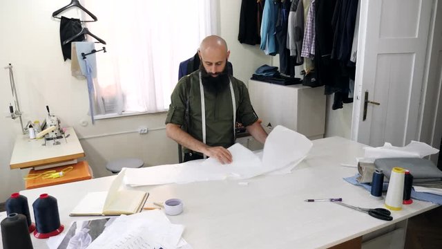 Tailor works with sketches in his workshop.