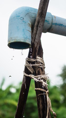 Fototapeta premium water flowing through old blue spout in rainy day