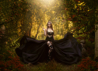 The dark queen of elves walks in the magical garden. A creative image, an unusual black dress....