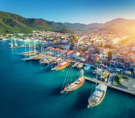 Wall murals Port Aerial view of boats and beautiful architecture at sunset in Marmaris, Turkey. Colorful landscape with boats in marina bay, sea, city, mountains. Top view from drone of harbor with yacht and sailboat
