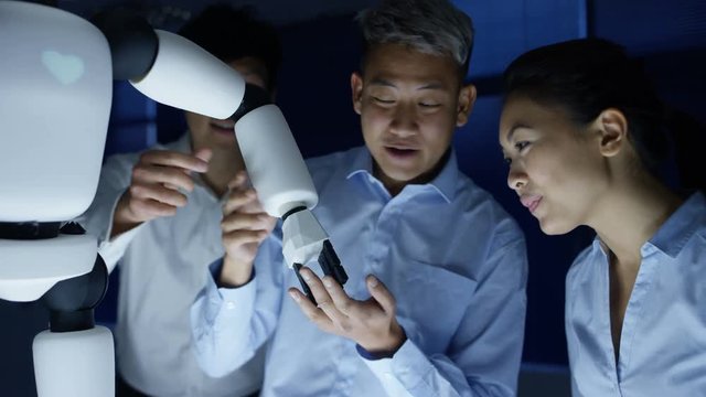  Electronics engineers collaborating on design of robot in dark lab