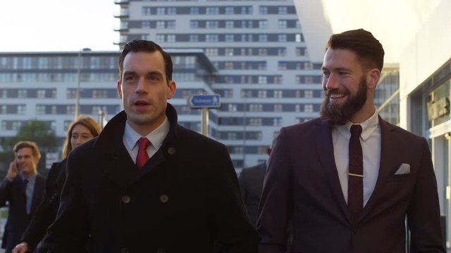 Diverse professional group walking in the city with 2 businessmen chatting