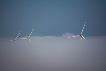 wind turbines engulfed in fog bank