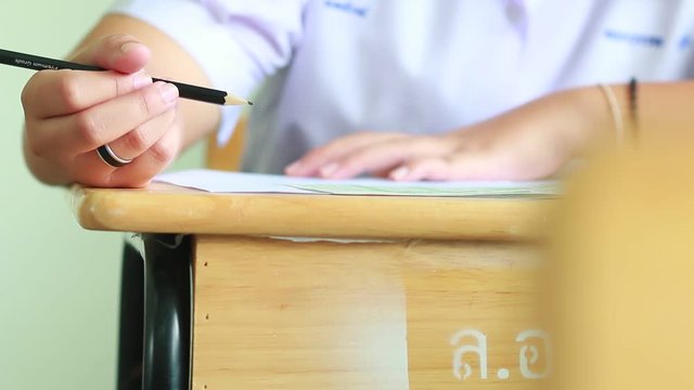 Asian students hands holding pencil taking fill drawing selected of choice on Exams paper sheet or test paper on wood desk in school, college with uniform. Education learning concept.
