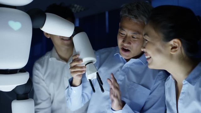  Electronics engineers collaborating on design of robot in dark lab