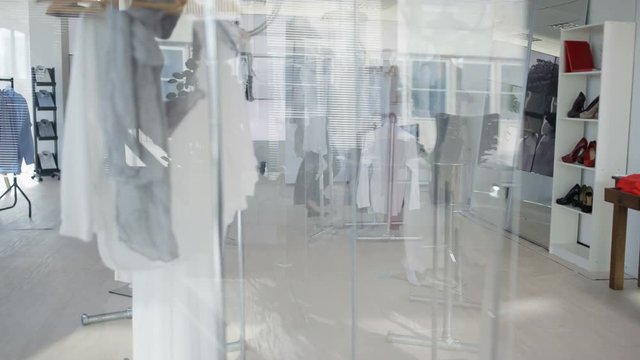 Cheerful couple shopping together, looking at clothes in boutique clothing store.