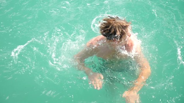 the man dives off the pier in the sea. 4k, slow motion