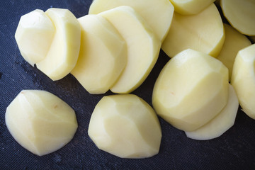 Raw peeled and sliced potatoes on cutting board