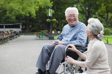 A lady walking in the park with a wheelchair husband