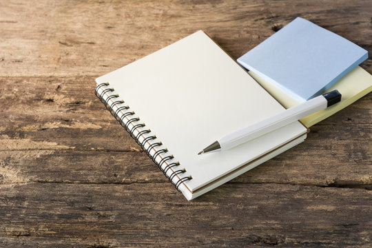 blank notebook pen and notice sticker on old wooden board. memo and planning concept.