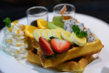 Waffle with mix fruit  and whipping cream  on a white plate