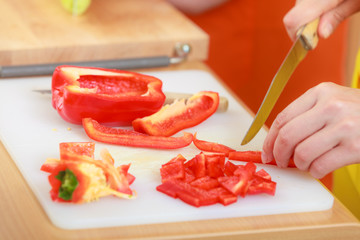 Woman preparing vegetables salad slicing red pepper