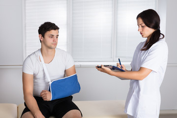 Doctor Giving Prescription To Injured Patient