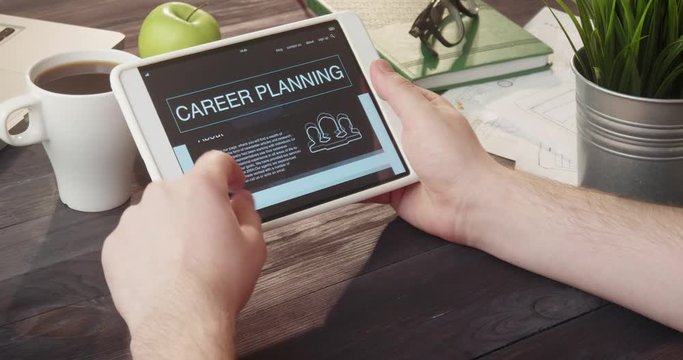 Reviewing career planning internet page using digital tablet at desk