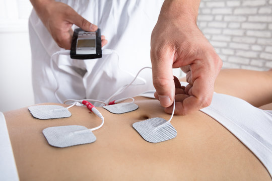 Therapist Placing Electrodes On Woman's Stomach