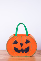 A trick- or -treat  pumpkin shaped basket with green handles. Copy space. 