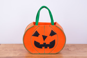 A trick- or -treat  pumpkin shaped basket with green handles. Copy space. Center 