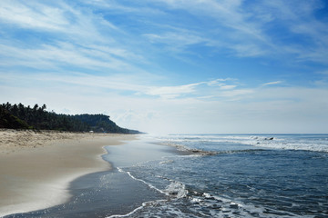 The ocean beach is in the horizon with small waves and haze.