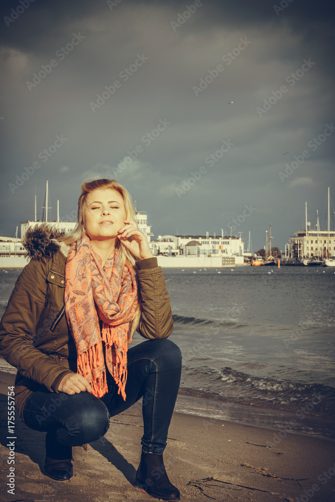 Wall mural woman relaxing on beach, cold day