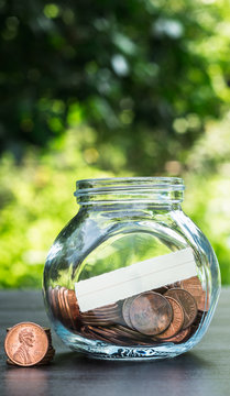 one cent coins in a glass jar on the table in a garden